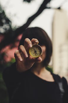 A woman extending a compass towards the camera, creating a focus on direction outdoors.