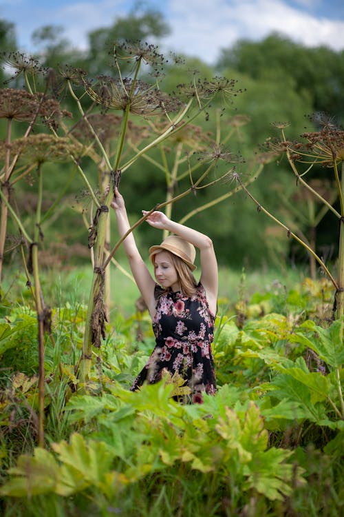 Woman in Floral Dress Posing Among Plants on Field