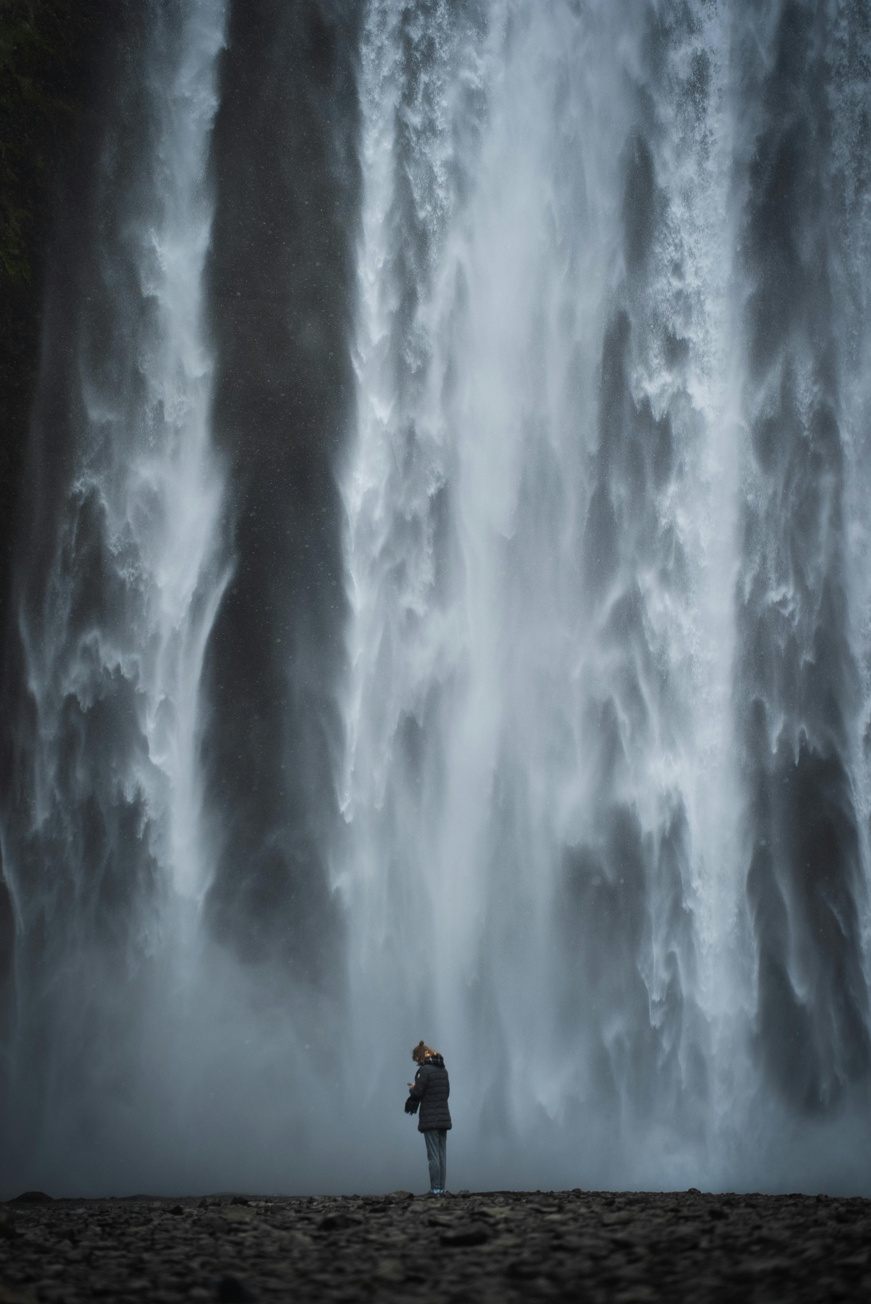 person standing under waterfall