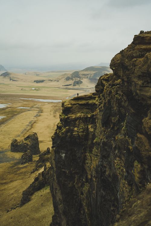 Free A breathtaking view from a cliff showcasing Iceland's rugged terrain under a cloudy sky. Stock Photo