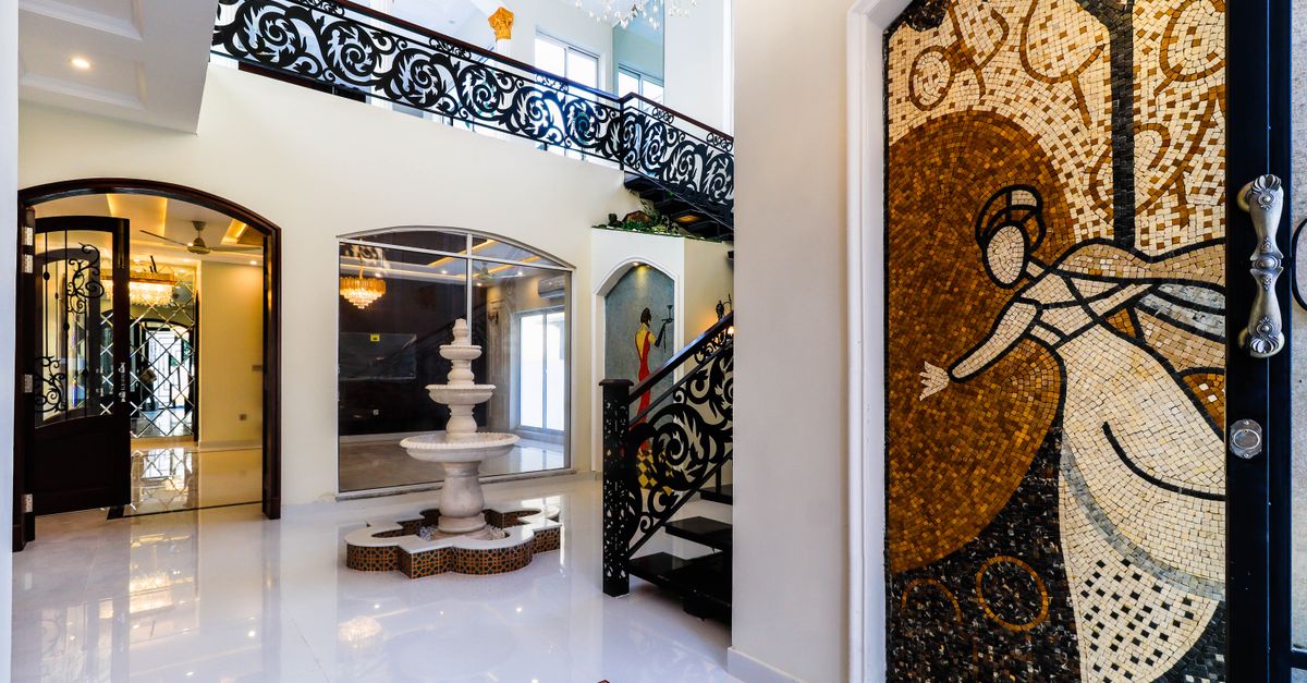 Luxurious interior showcasing artistic mosaics and a marble fountain under ornate railings.