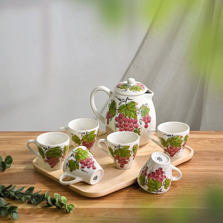 White Porcelain Tea Set Decorated With Grapes Motif Standing On A Wooden Tray