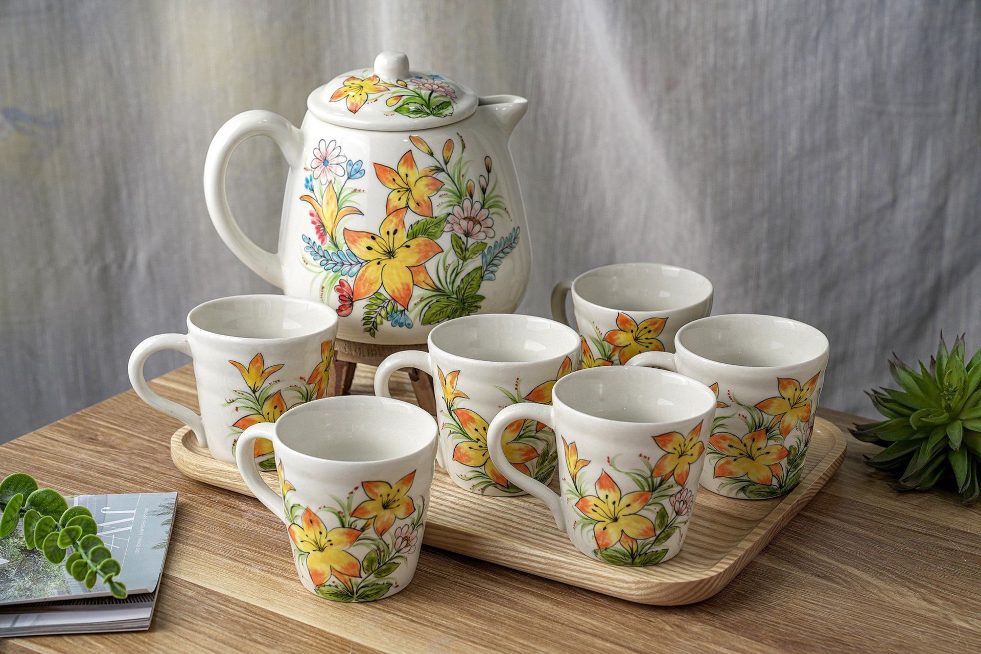 Charming floral tea set with hand-painted porcelain cups and teapot on a wooden table.