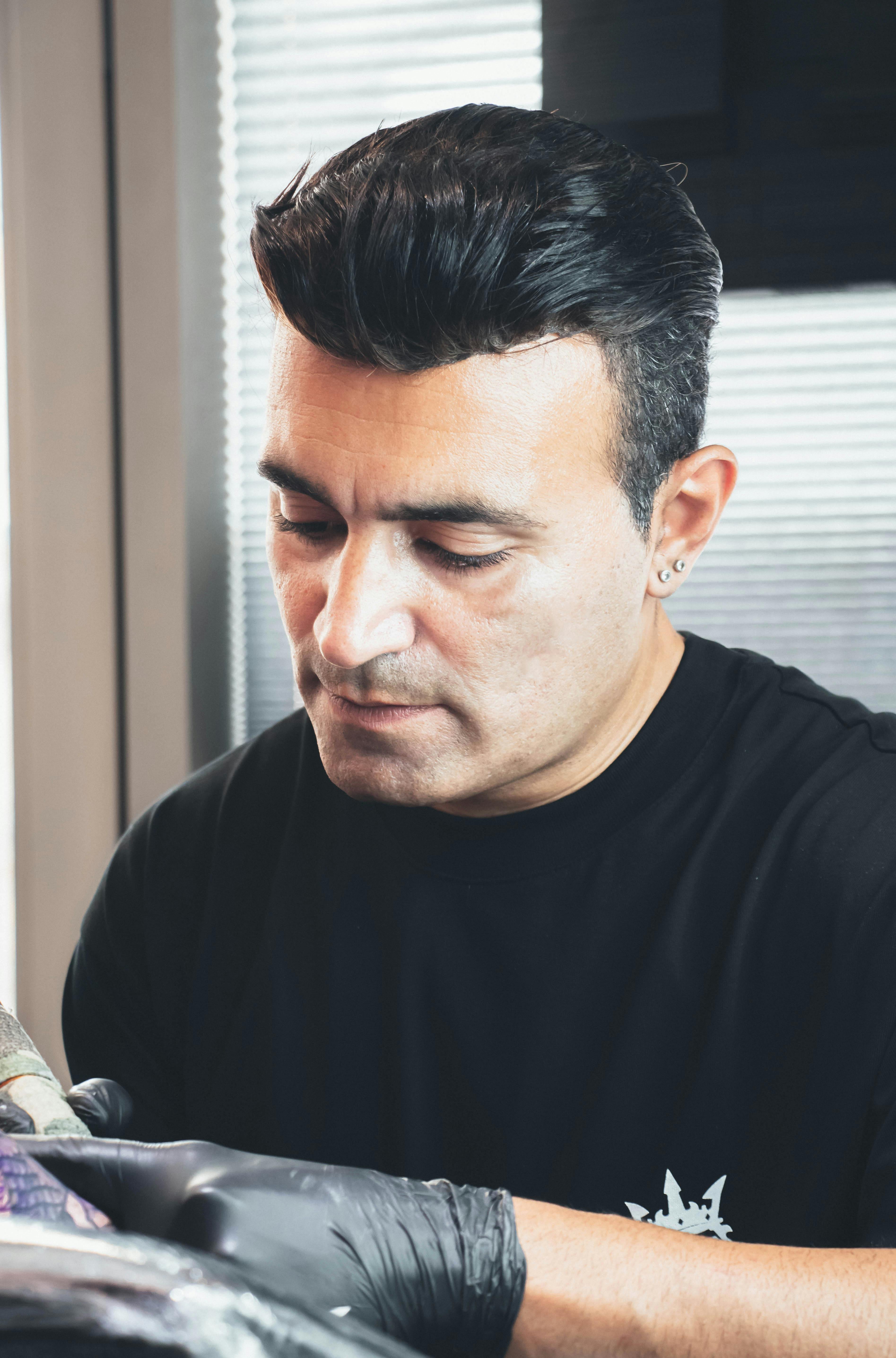A focused tattoo artist working on a detailed design with precision.