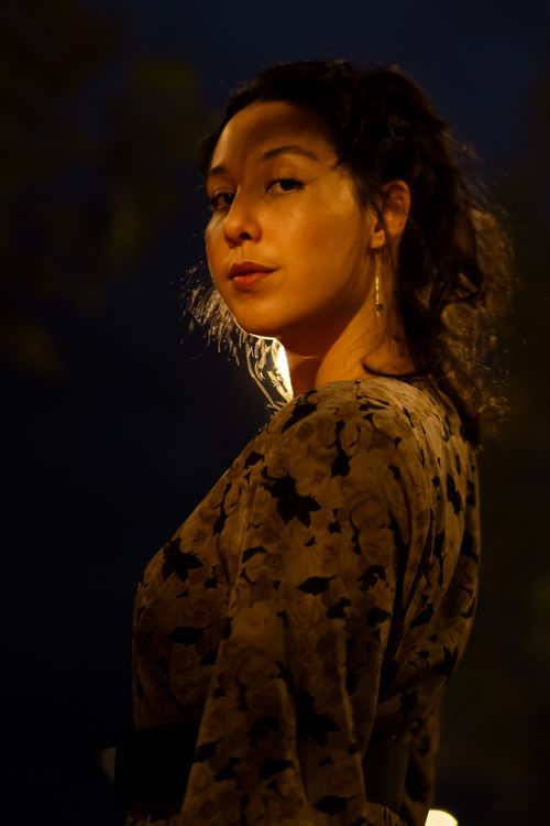 Free A woman wearing a floral dress poses under streetlights at night, creating a dramatic and moody atmosphere. Stock Photo