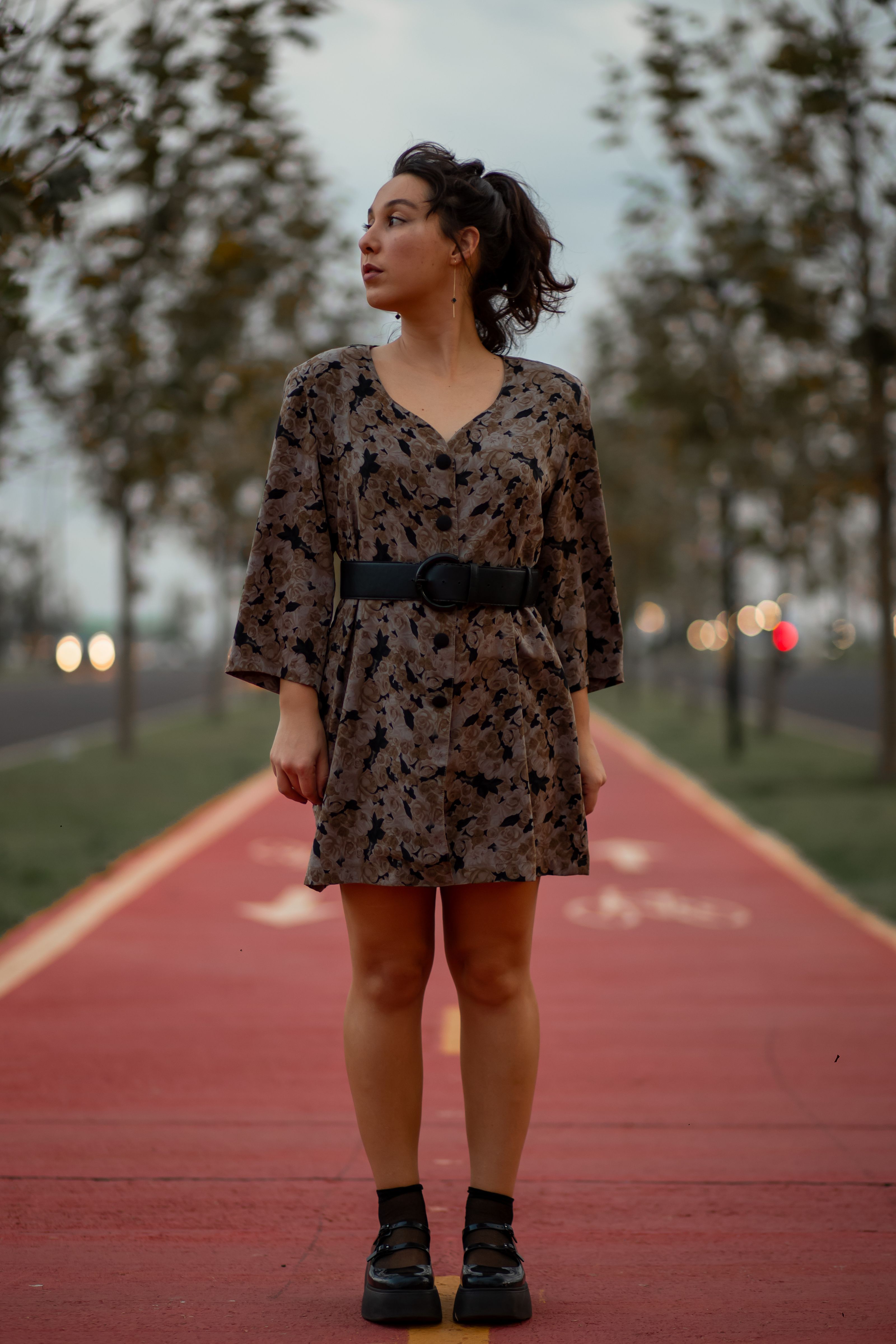 Uma mulher fashionable em um vestido em uma ciclovia da cidade durante o crepúsculo.