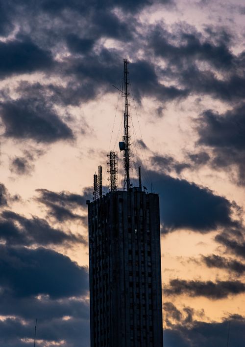 Free Silhouette of a skyscraper with antennas against a dramatic sunset sky. Stock Photo