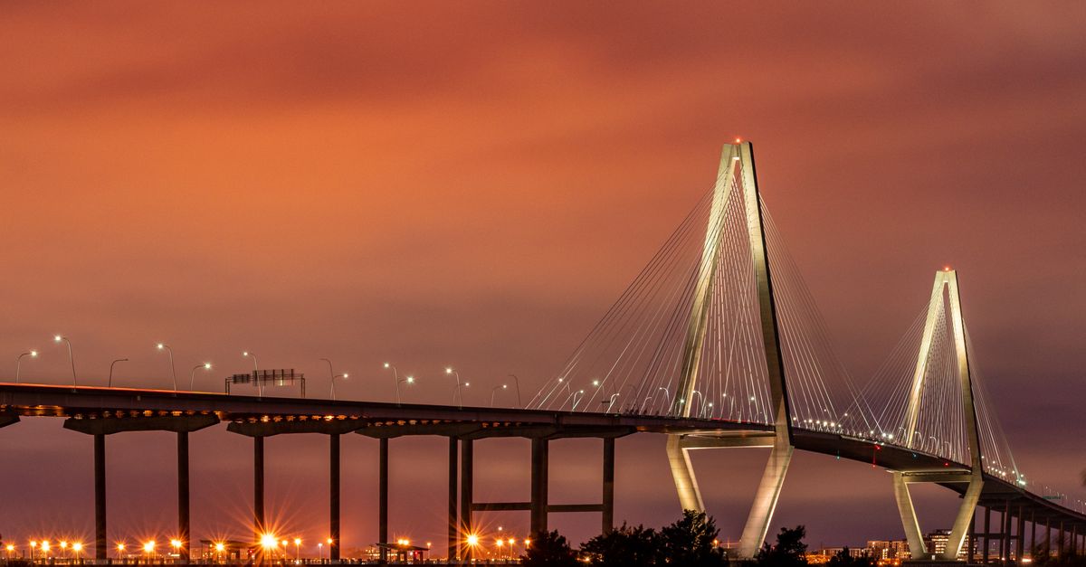 Stunning view of the illuminated Arthur Ravenel Jr. Bridge in Charleston, SC during sunset.