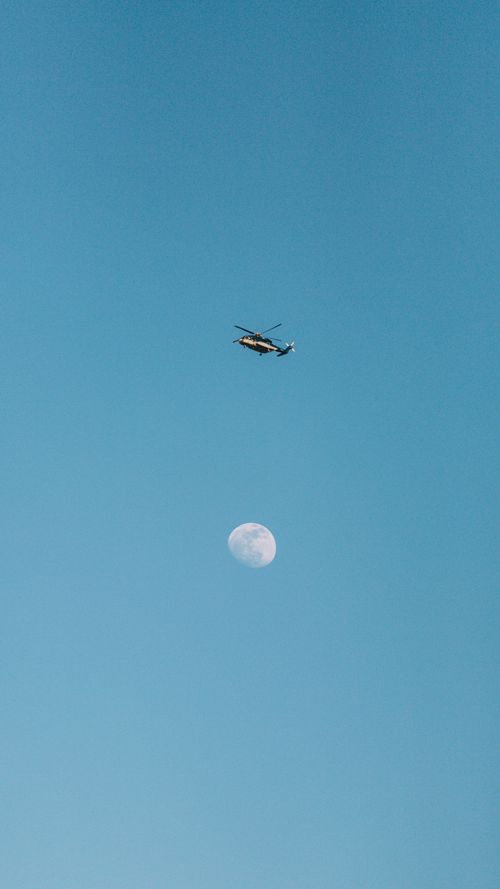 Free A helicopter flies gracefully above the moon against a blue sky in Mecca, Saudi Arabia. Stock Photo