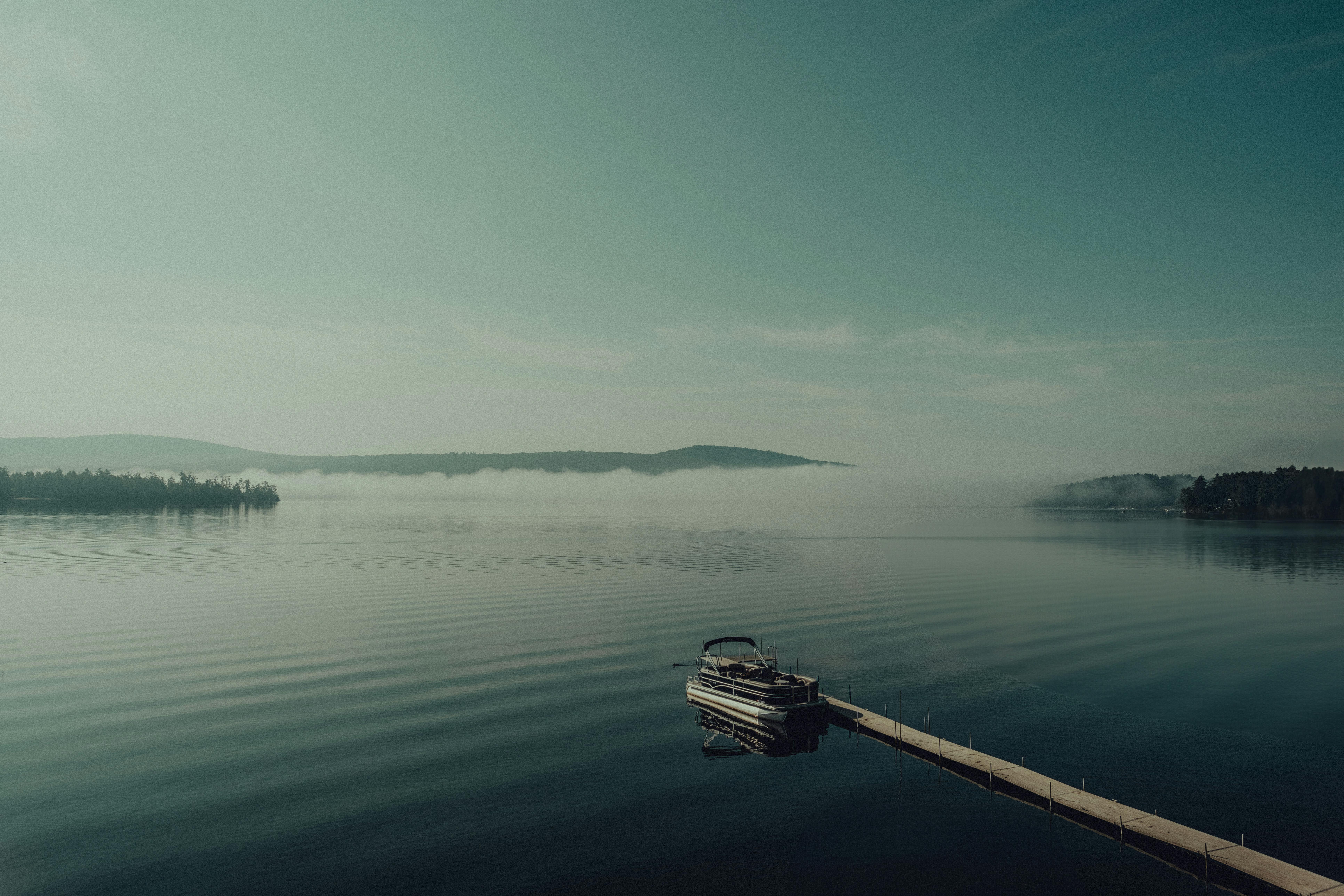 A boat floating on a lake with mist in the air