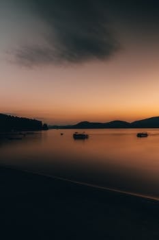 A calming sunset view over a peaceful lake with subtle reflections creating a serene atmosphere.