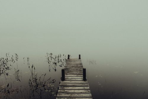 Free A mysterious foggy lake with an empty wooden pier extending into the mist, creating a haunting atmosphere. Stock Photo