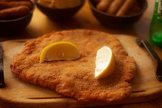 Golden-brown schnitzel topped with lemon wedges on a wooden board, perfect for food photography.