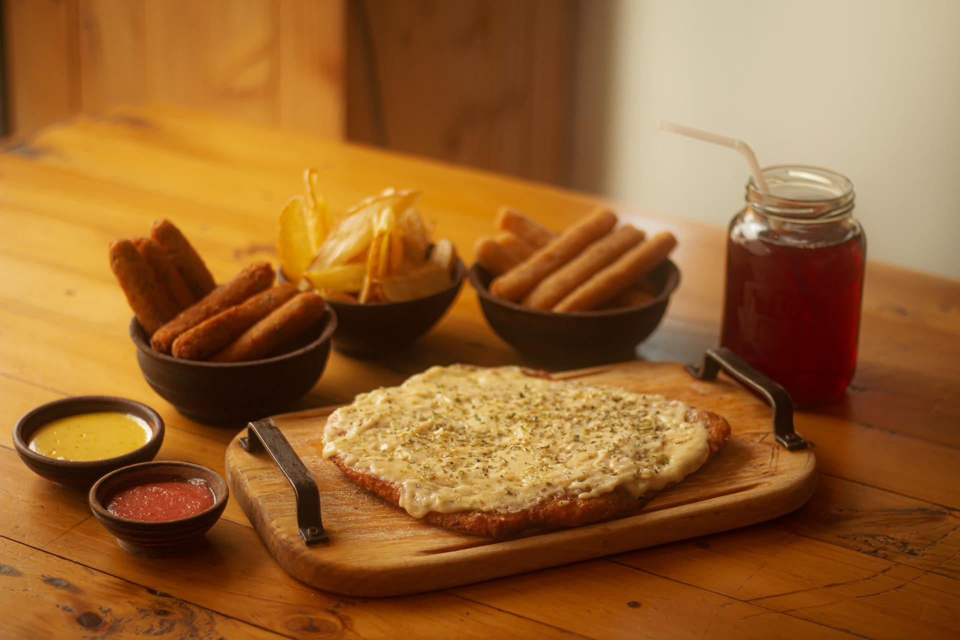 Tantalizing Bolivian meal featuring cheese-topped bread and fried snacks on a wooden table.