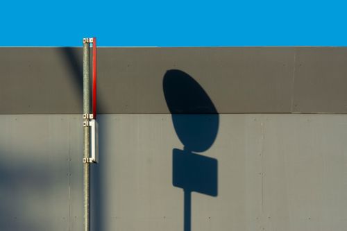 Free Abstract urban scene with shadowed sign against a wall under a clear blue sky. Stock Photo