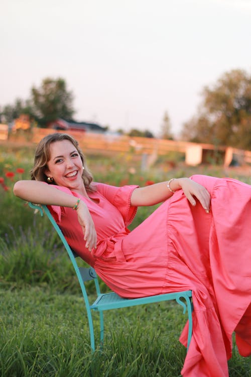 Smiling Woman in Pink Dress Sitting on Chair