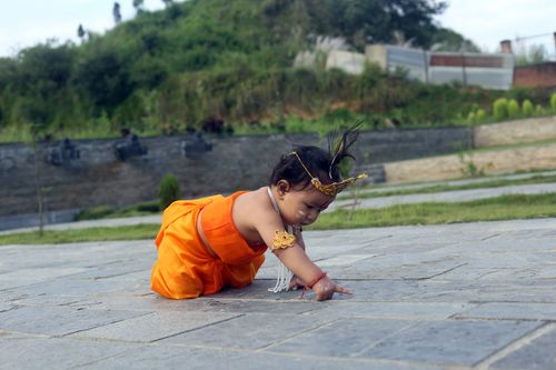 Free Adorable baby dressed as Krishna playing outdoors on a sunny day. Stock Photo