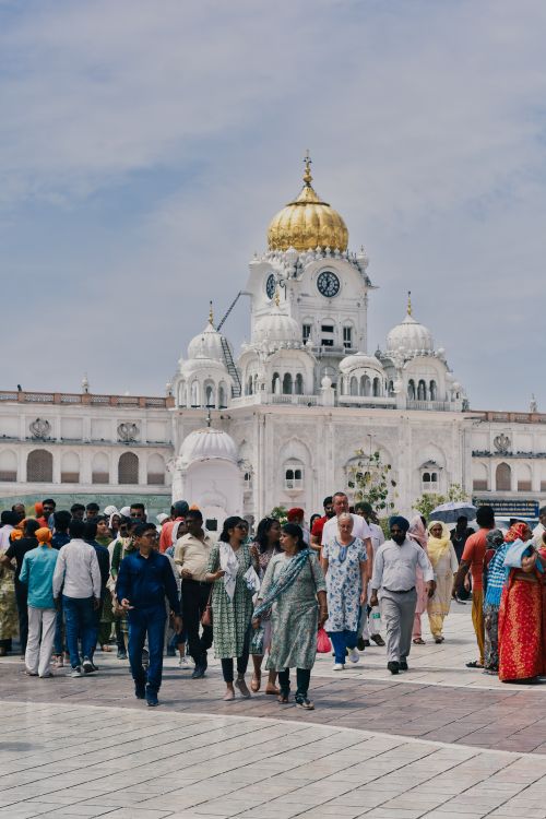 Free Visitors gather at the iconic Golden Temple Plaza in Amritsar, showcasing vibrant cultural diversity. Stock Photo