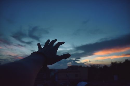 Free A hand reaching out against a colorful twilight sky in Odisha, capturing a dramatic moment of silhouette and light. Stock Photo