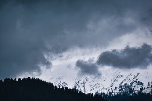 Free A dramatic view of storm clouds over the snow-capped mountains in Pahalgam, exuding a moody and serene atmosphere. Stock Photo