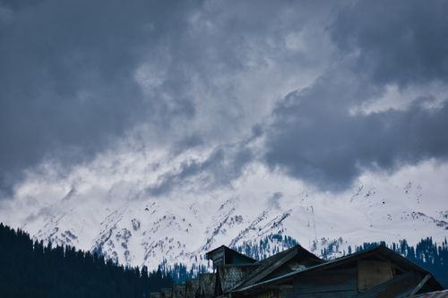 Free Snow-covered mountains under dramatic cloudy sky in Pahalgam, perfect for winter landscape enthusiasts. Stock Photo