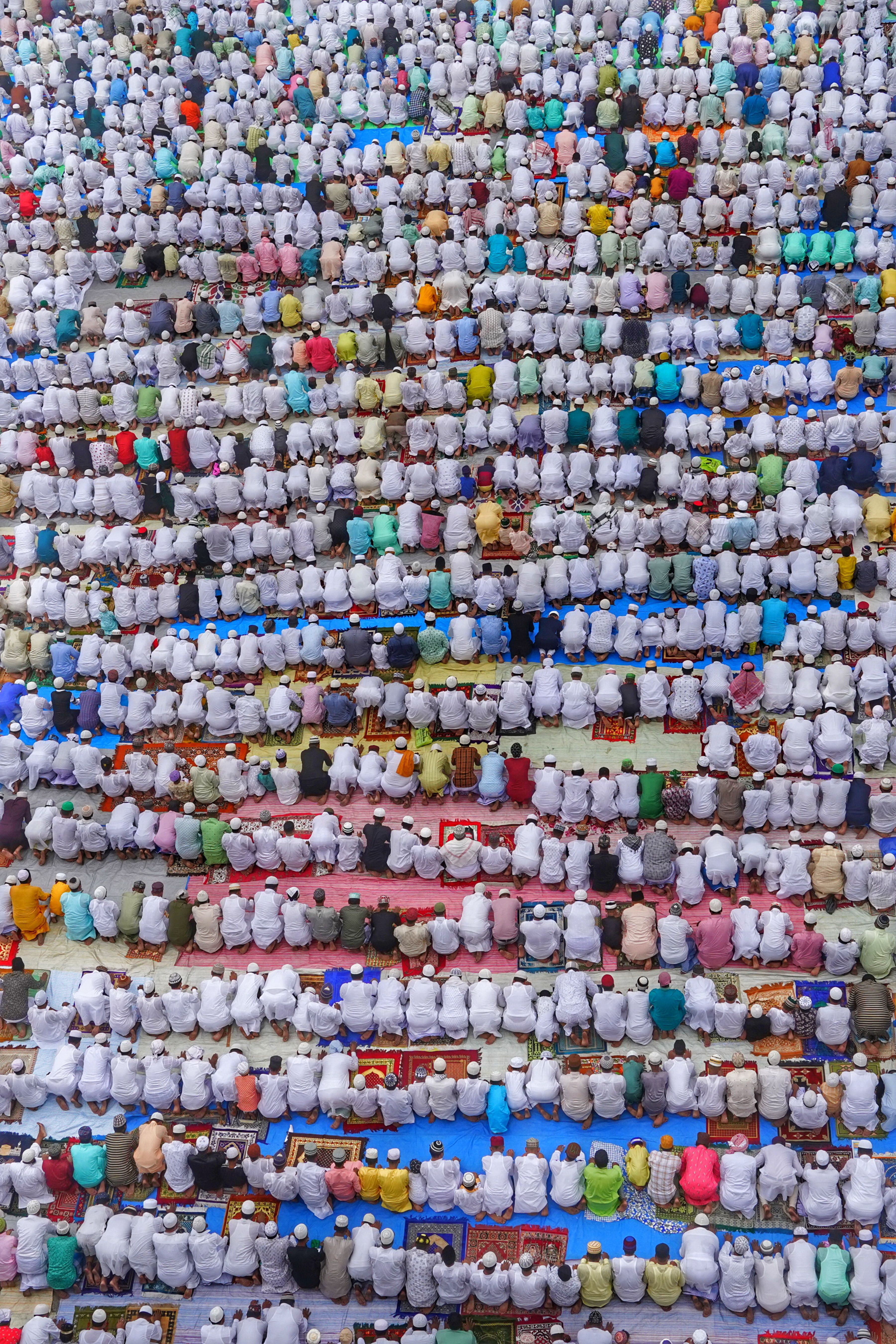 Top view of a large gathering in traditional clothing engaged in prayer.