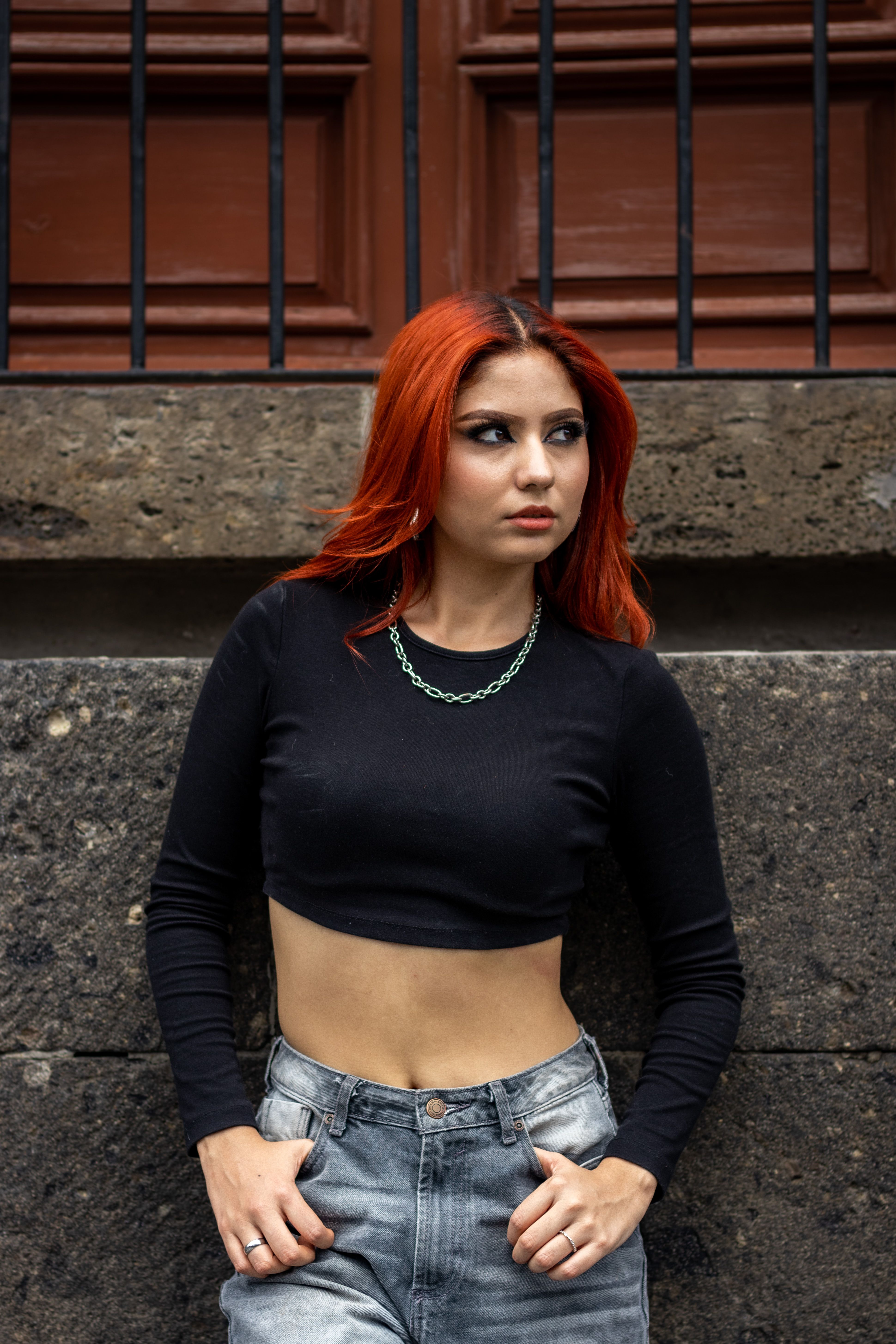 A woman with red hair posing in front of a wall · Free Stock Photo
