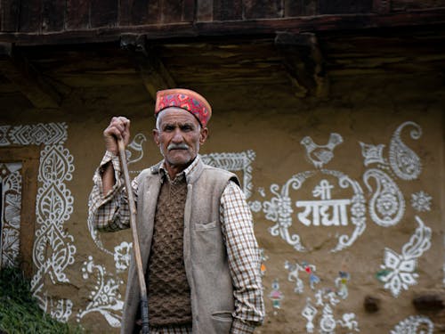 Old Man with Cane near Traditional House Ornate Wall