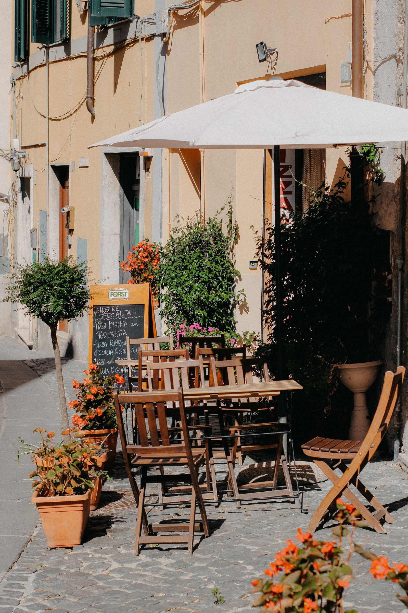 Cafe tables with flowers and plants on a cobbled lane