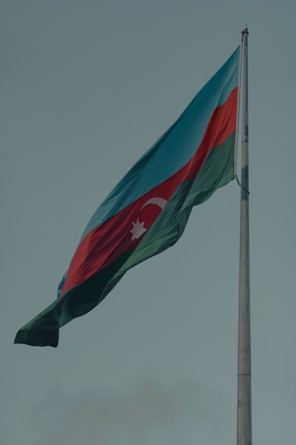 Vertical shot of Azerbaijani flag on a flagpole against a clear sky, symbolizing national pride.