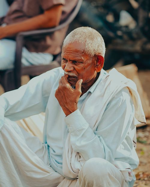 Free Thoughtful senior man in white kurta outdoors, Lucknow, India, reflecting serenity Stock Photo