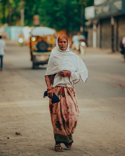 Free An elderly Indian woman in traditional attire walks down a street in Lucknow, India, embodying cultural heritage. Stock Photo