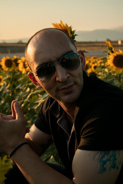 A Man Sitting on a Sunflower Field 
