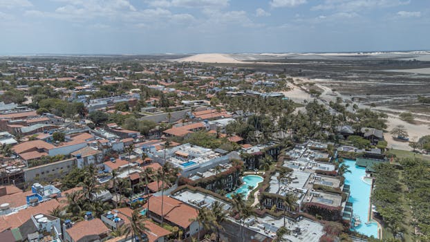 Explore scenic Jericoacoara with sand dunes, palm trees, and pools from above.
