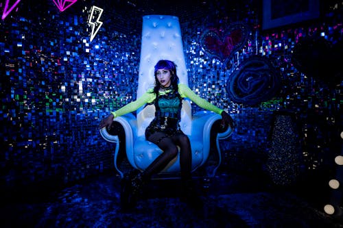 Punk Rock Singer Sitting on a White Armchair with a High Backrest