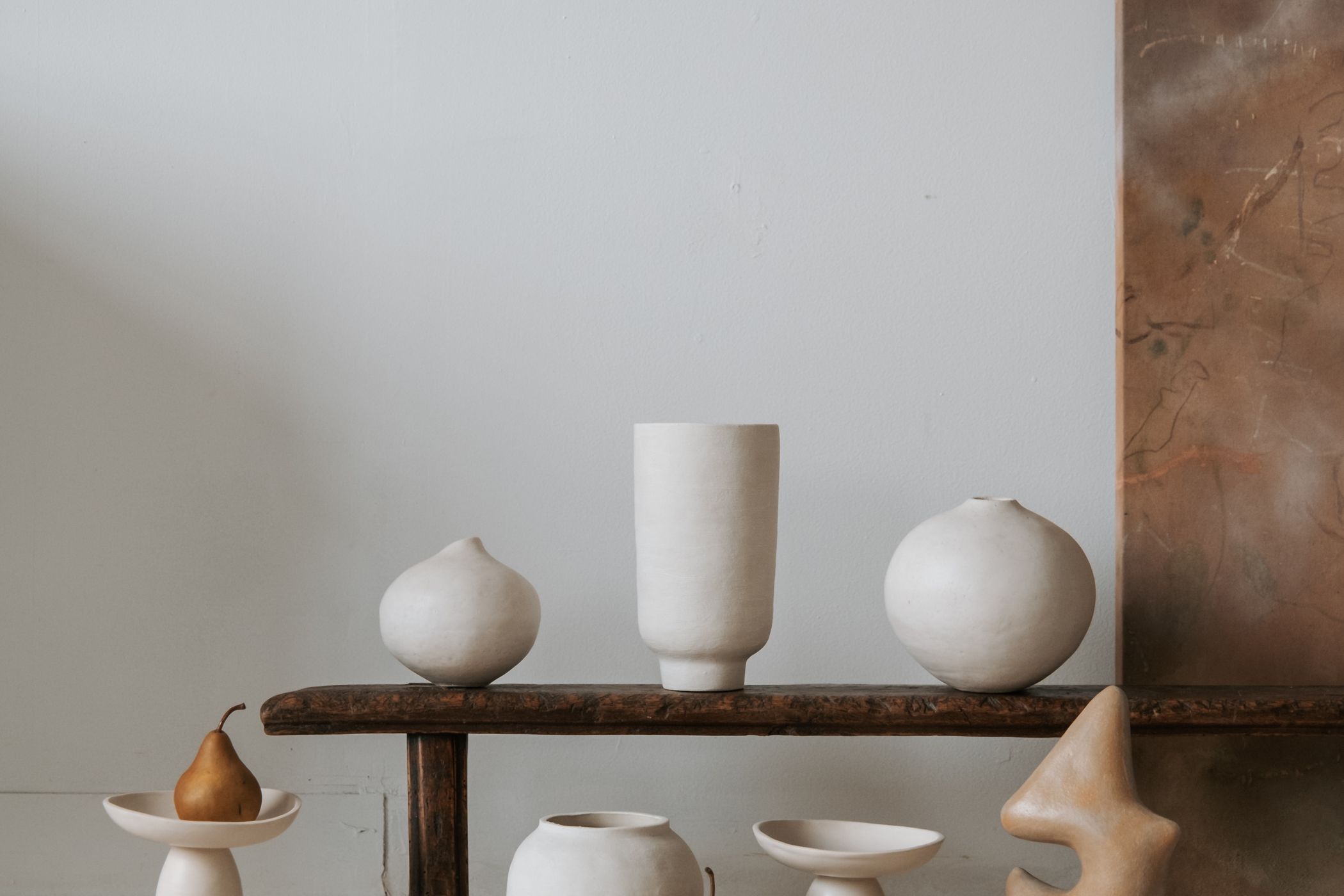 Ceramic vessels arranged on a wooden bench in a quiet studio