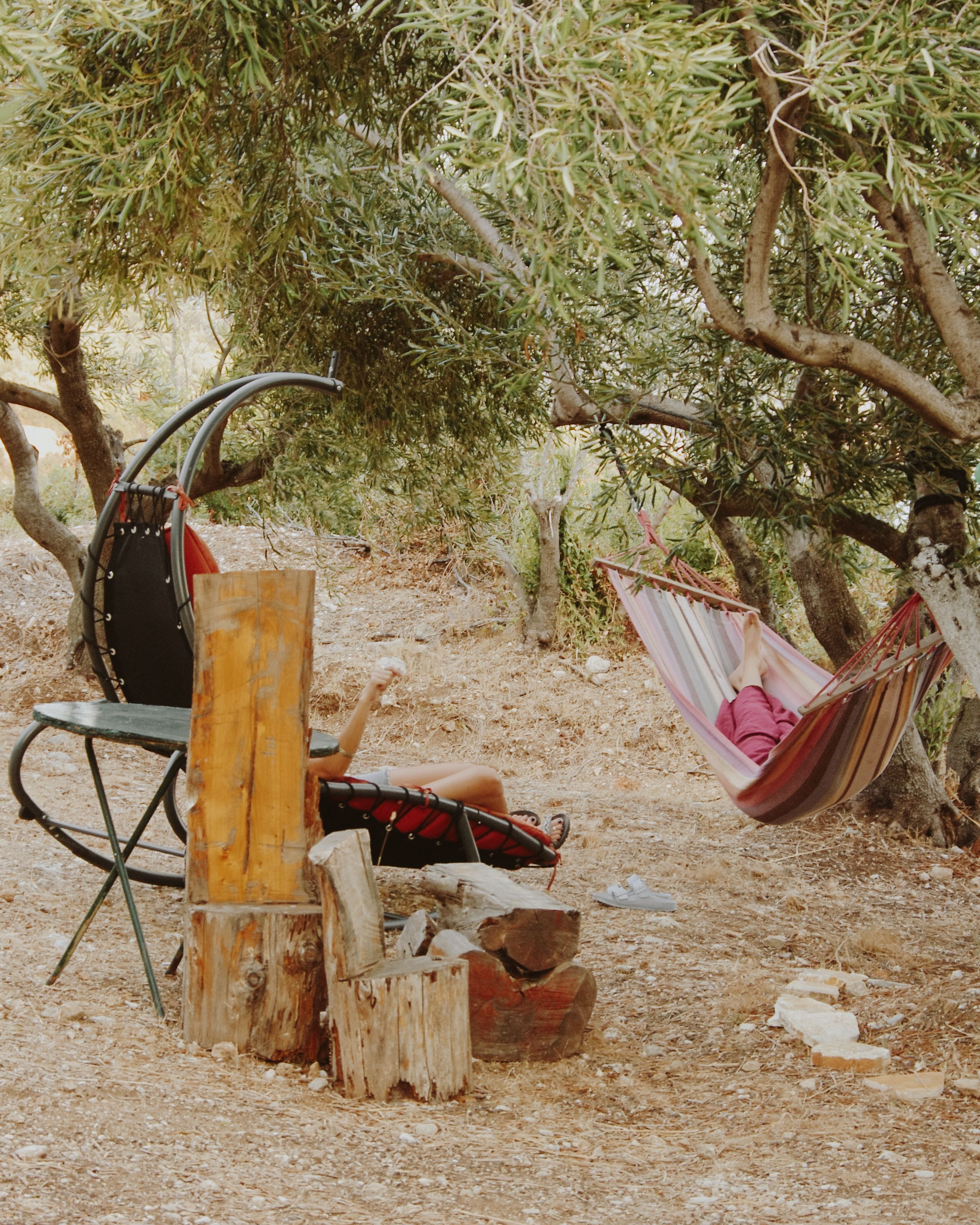 Serene scene of a person relaxing in a hammock under olive trees, creating a peaceful summer retreat in Corfu, Greece.