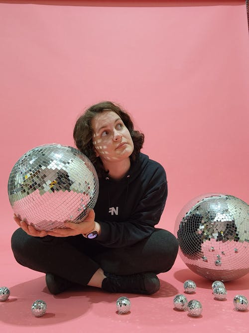 Woman Posing with Disco Balls on Pink Background