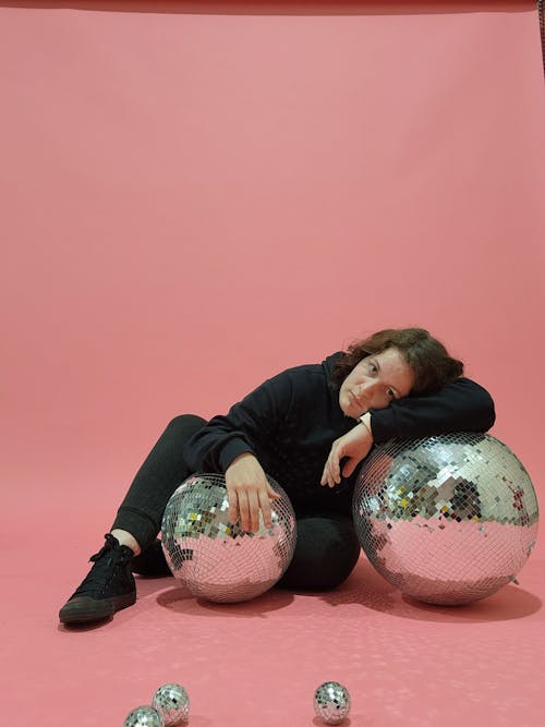Woman in Sportswear Posing with Disco Balls on Pink Background