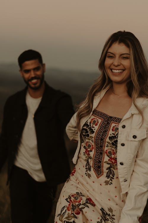 Smiling Woman in Jacket and Dress with Man behind