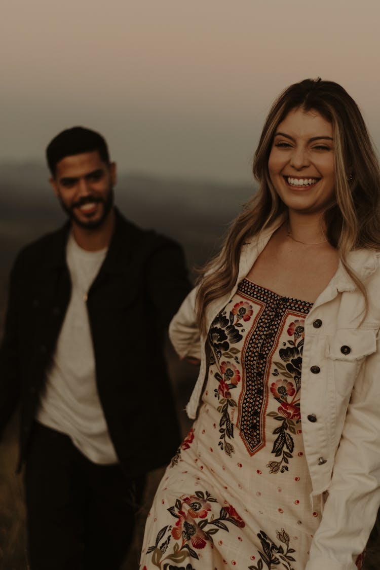 Smiling Woman In Jacket And Dress With Man Behind