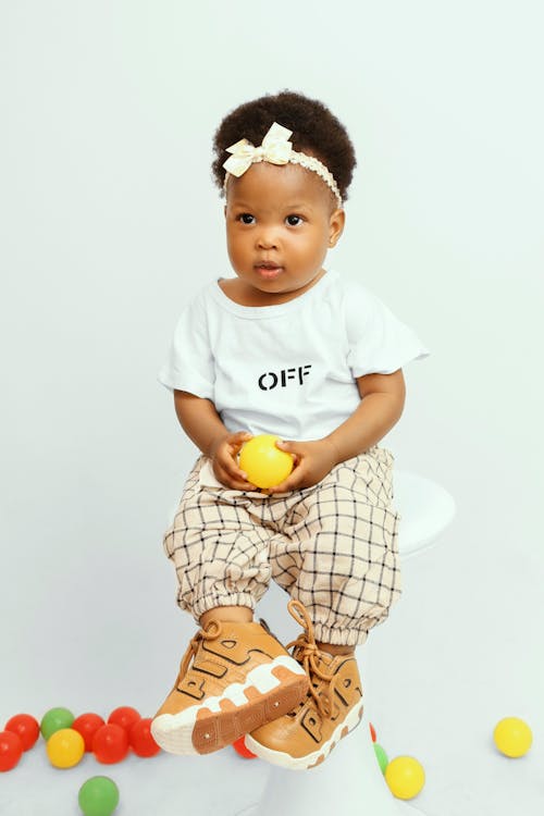 Free Studio Shot of a Little Girl Holding a Yellow Plastic Ball Stock Photo