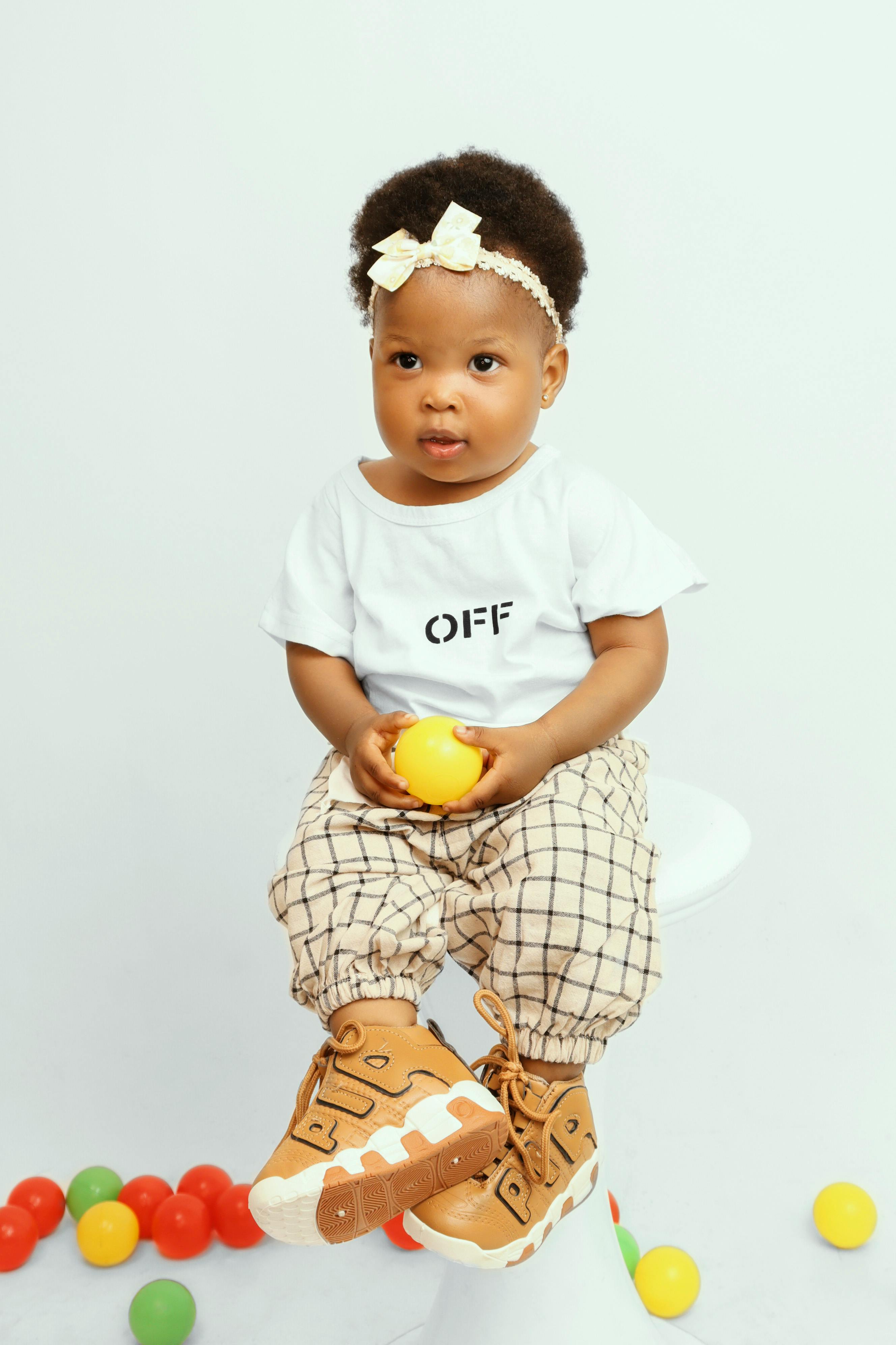 gratis Studiofoto Van Een Klein Meisje Dat Een Gele Plastic Bal Vasthoudt Stockfoto