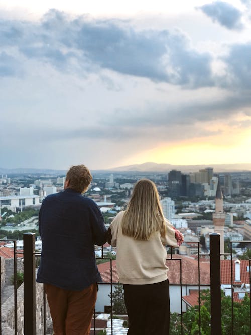 Woman and Man Standing Together with City behind at Sunset
