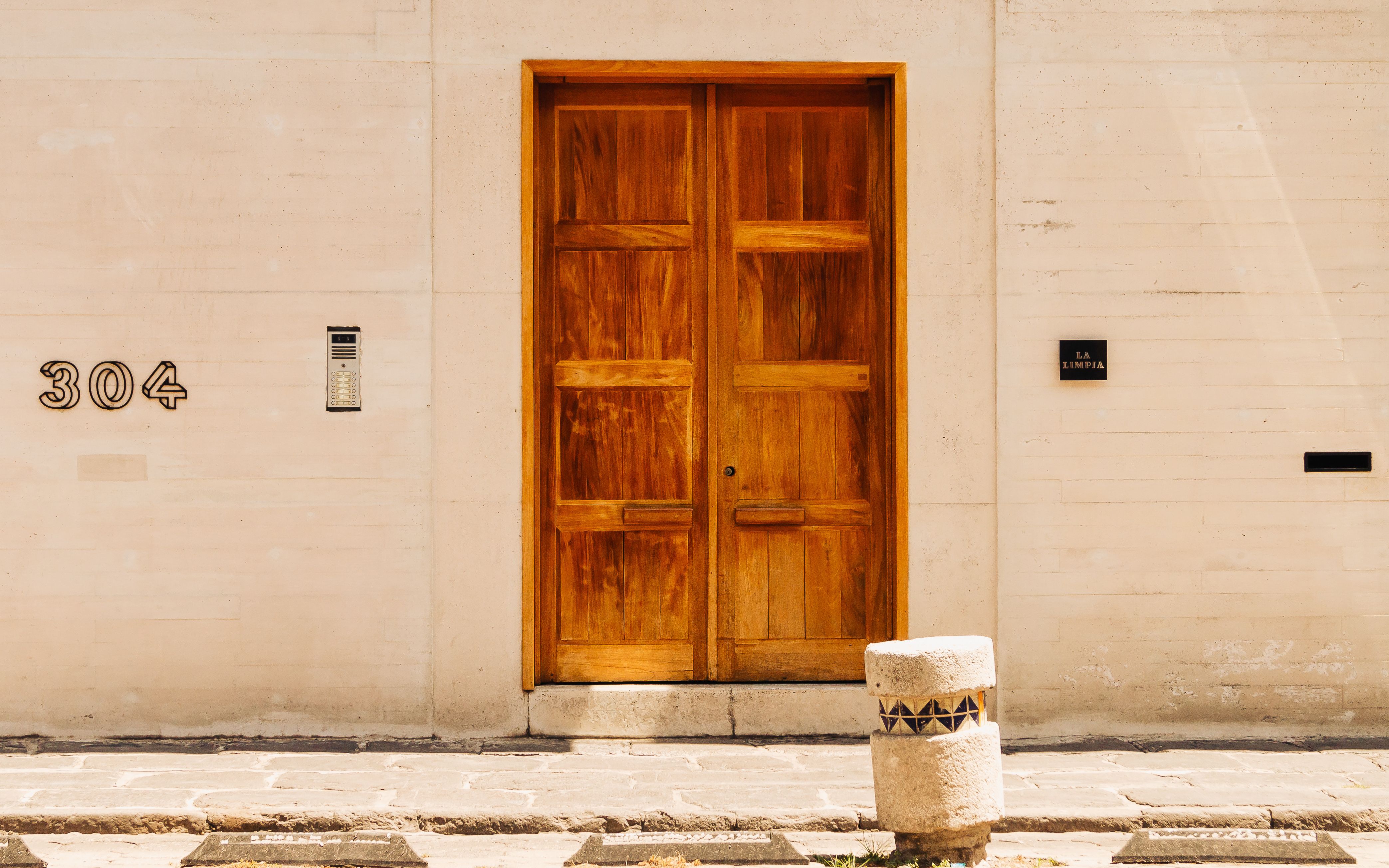 A stylish wooden door marked with 304, set against a minimalist wall, offering architectur