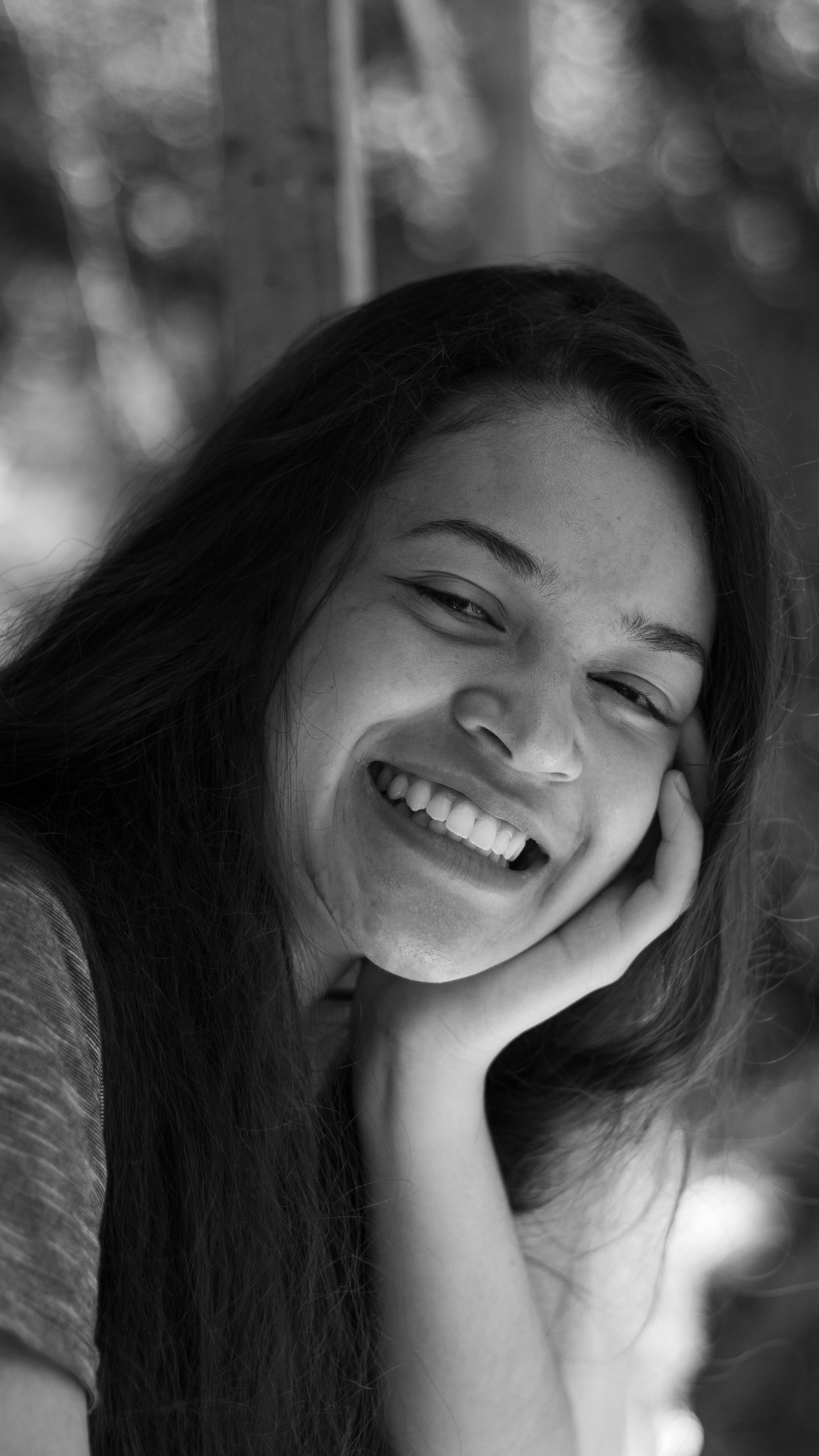 A cheerful black and white portrait of a young woman smiling warmly outdoors.