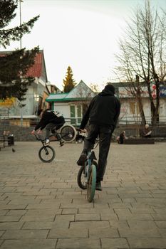 Two BMX riders showcase thrilling tricks in a lively urban park setting.
