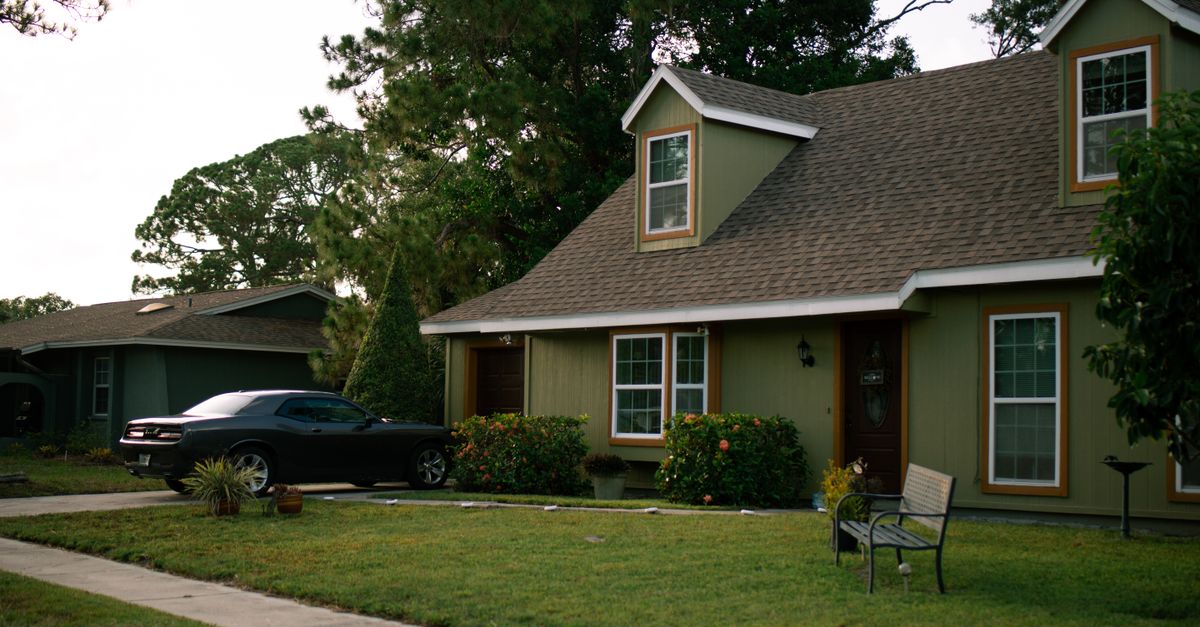 A beautiful suburban home with a well-maintained green lawn and parked car, highlighting residential comfort.