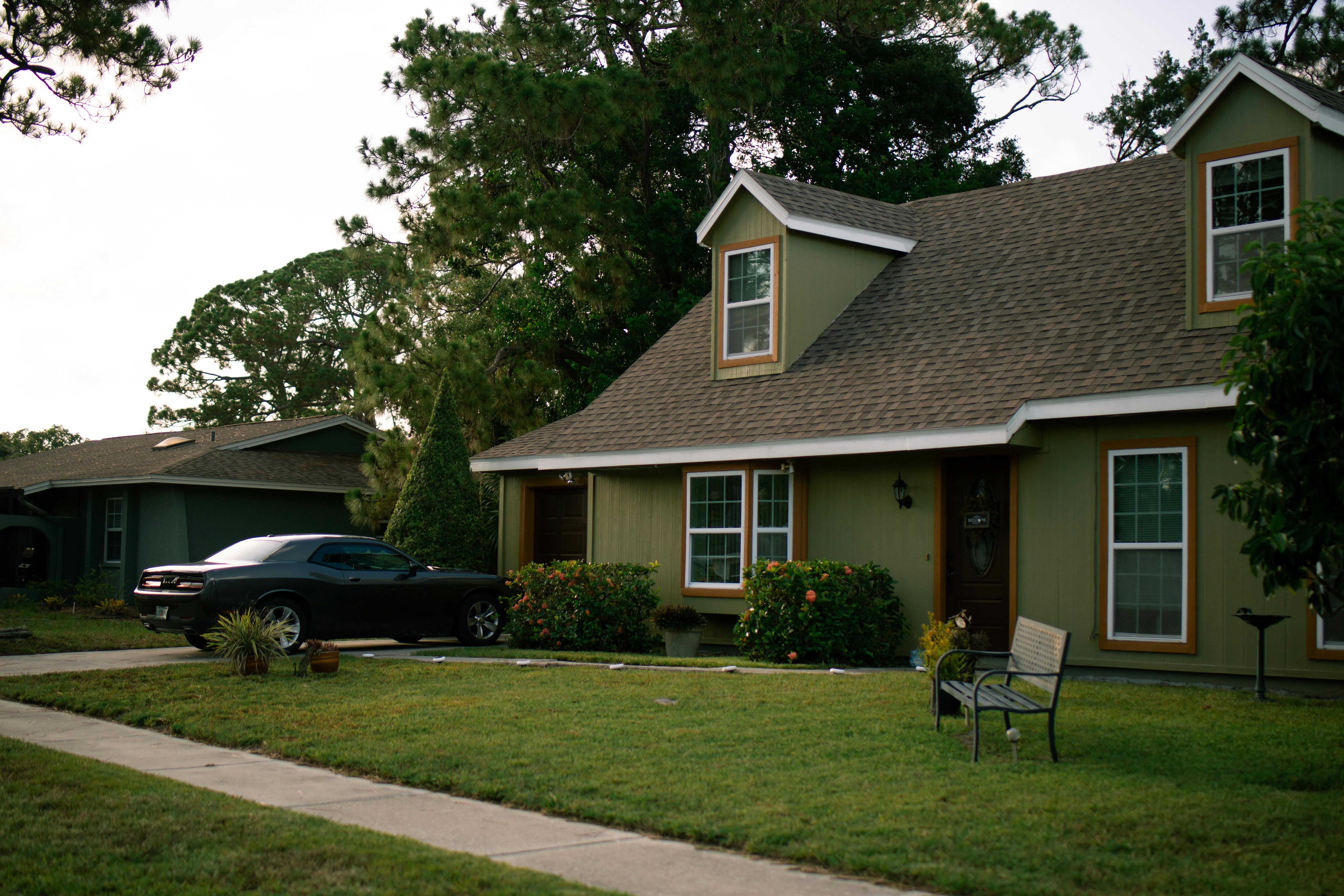 Free A beautiful suburban home with a well-maintained green lawn and parked car, highlighting residential comfort. Stock Photo