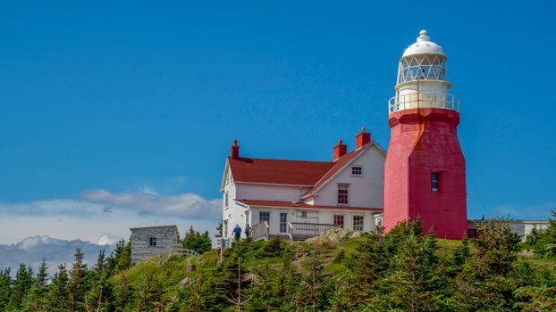 Long Point Lighthouse in Newfoundland under a clear blue sky during summer.
